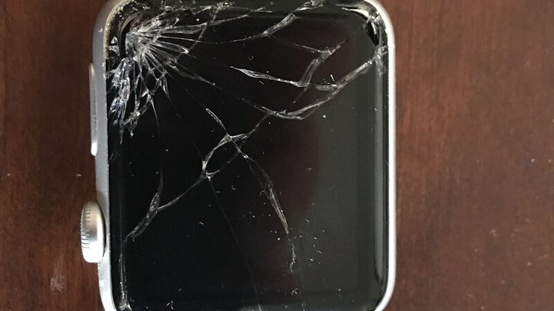 Apple Watch with a badly shattered screen on a wooden table (earlier model, similar damage)