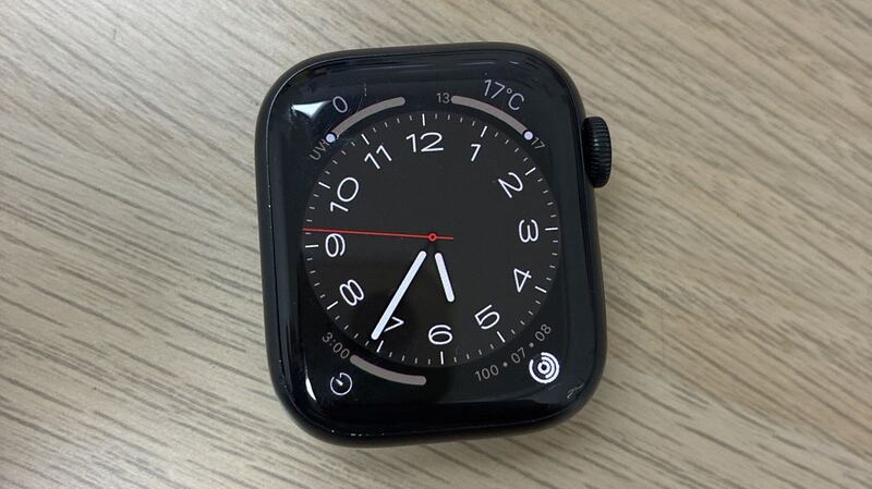 Apple Watch Series 8 in midnight aluminum with a chipped screen edge, on a wooden desk
