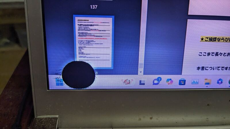 Close-up of a damaged laptop LCD with a dark blot spreading near the taskbar (similar laptop, not a Zenbook)