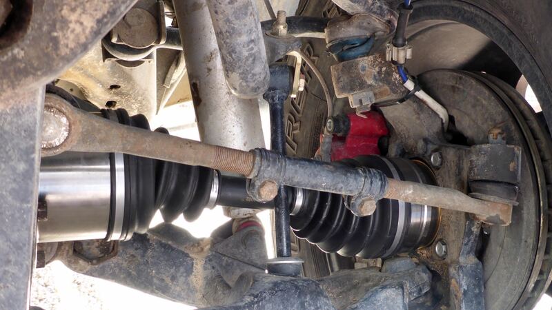 Underside of a pickup front wheel with red brake caliper, axle and tie rod (similar vehicle)