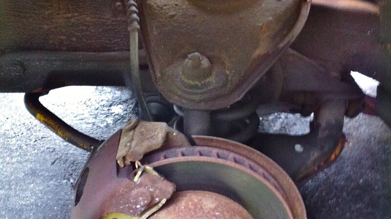Rusty front brake rotor and caliper with the wheel removed (similar vehicle)