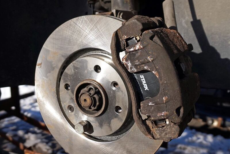 Car disc brake with the wheel removed, showing a worn brake pad in the caliper over the rotor (similar vehicle)