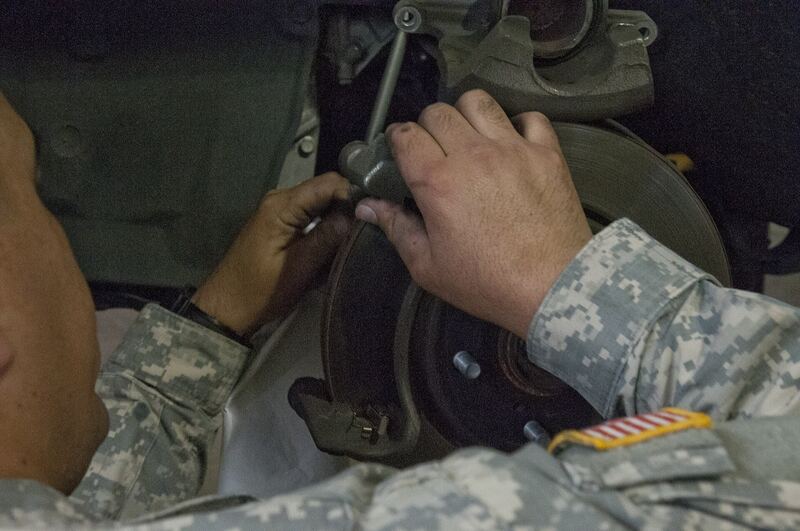Technician fitting new brake pads into a caliper over a disc rotor (similar vehicle)