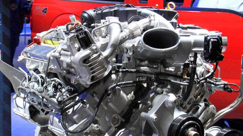 Ford 6.7L Power Stroke V8 turbo diesel engine on display in front of a red Super Duty