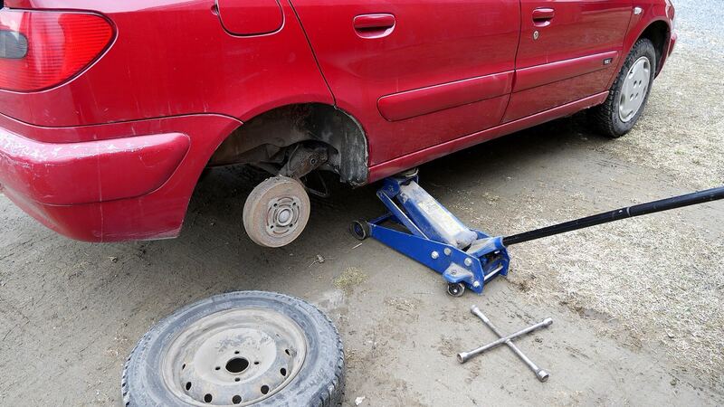 Car on a floor jack with the wheel removed and the tire on the ground