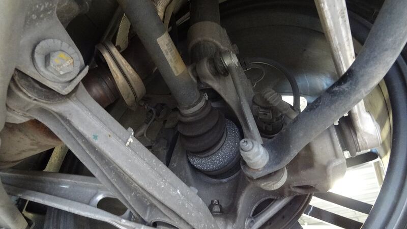 Close-up of a car's suspension arms, axle and spring under the wheel well, similar vehicle