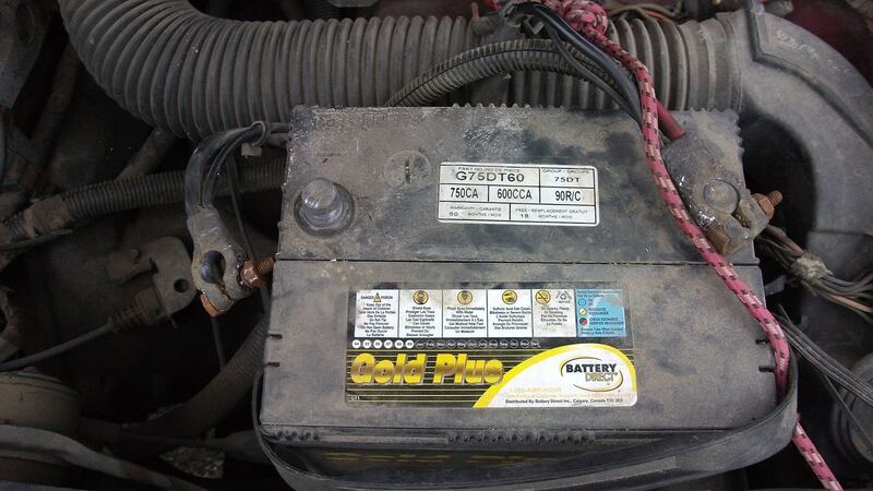 Car battery in an engine bay with the negative cable being disconnected, similar vehicle