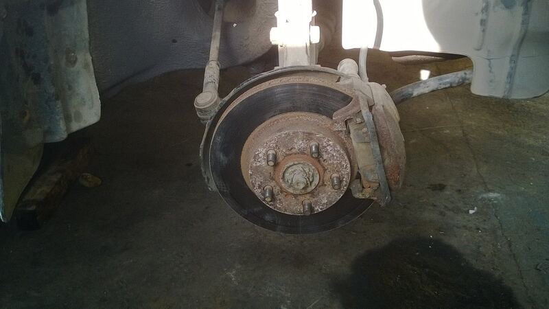 Front disc brake and strut with the wheel removed in a garage, similar vehicle