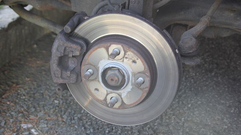 Car disc brake with the wheel removed showing rotor and caliper, similar vehicle