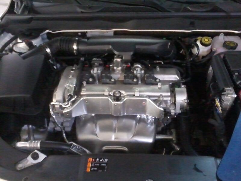 Engine bay of a GM car with a four-cylinder Ecotec engine, hood open (similar vehicle)