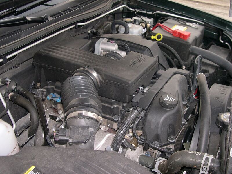 Hood up on a GMC truck, showing the engine bay, AC lines and battery (similar vehicle)