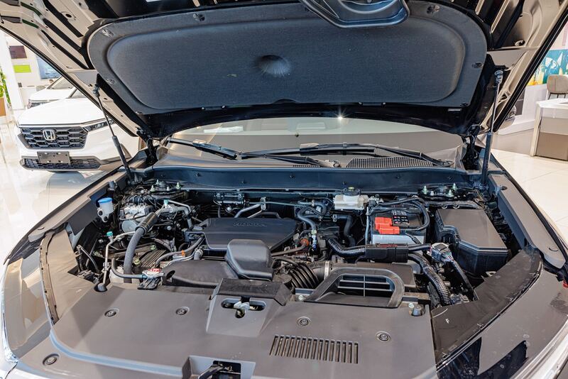Hood open on a sixth-generation Honda CR-V engine bay with the 12V battery at right