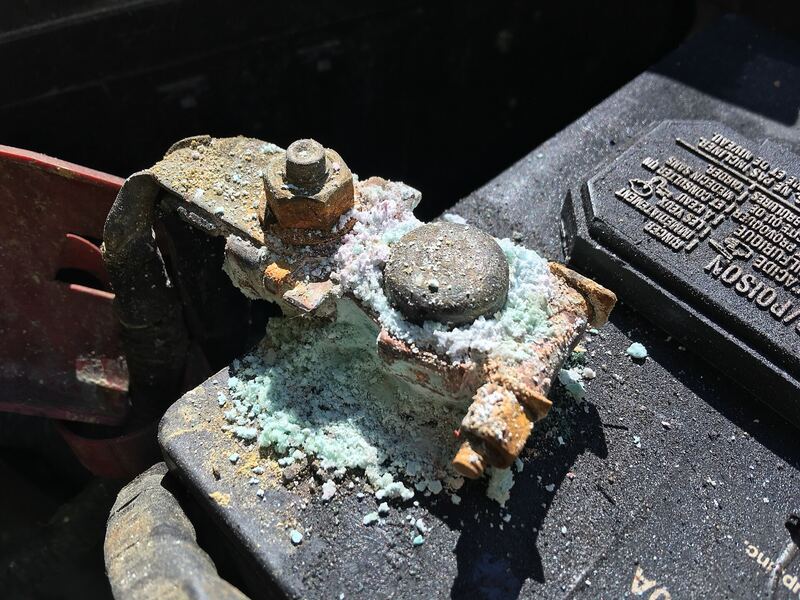 Car battery terminal covered in white and green corrosion