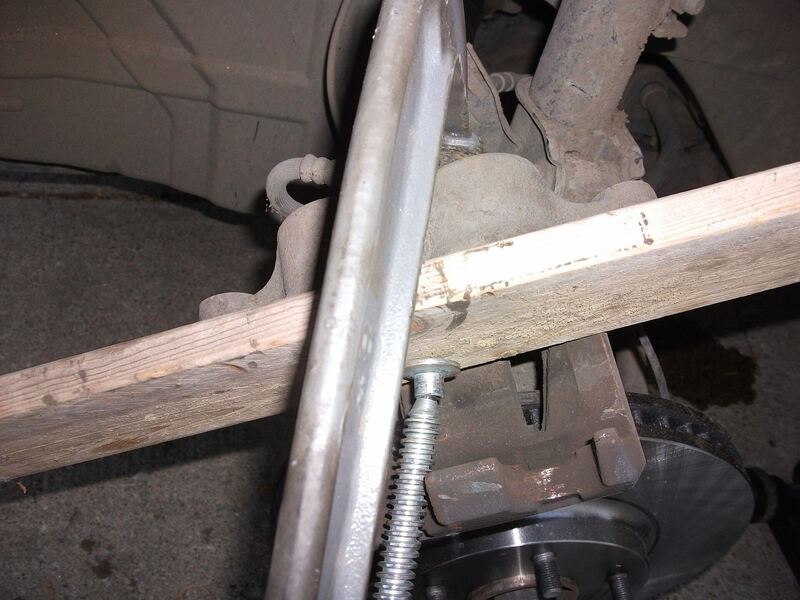 Mechanic's tool pushing a brake caliper piston back during a pad change, wheel removed (similar vehicle)
