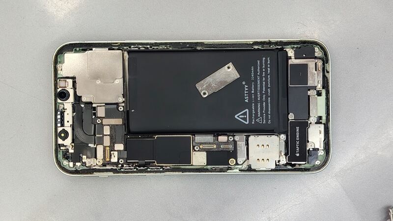 Opened iPhone 12 with the screen removed, showing the battery and logic board