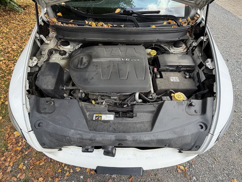 White Jeep Cherokee KL with the hood open showing the 3.2L V6 engine and battery box