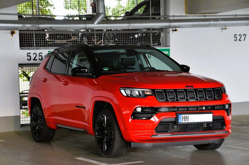 Red Jeep Compass with a black roof parked in a garage, front three-quarter view