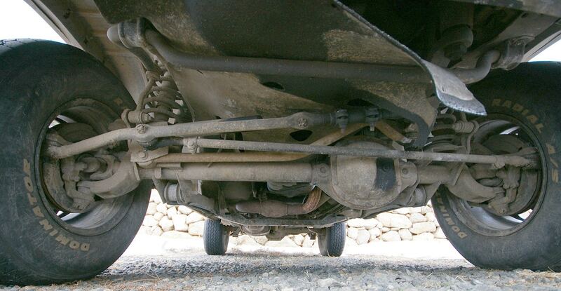 A solid front axle with coil springs and steering linkage, seen from underneath