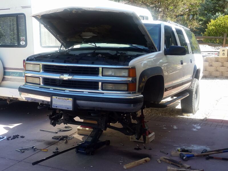 SUV raised on jack stands with the front wheels off and brake rotors exposed, similar to a Sportage brake job