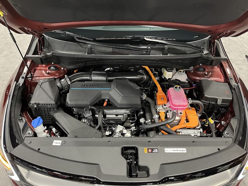 Engine bay of a red Kia Sportage Hybrid with the hood open at the 2023 Denver Auto Show