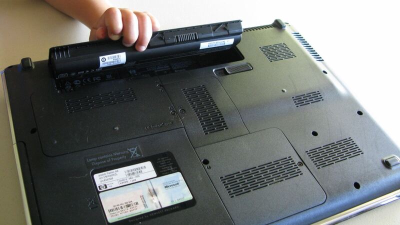 Laptop battery being lifted out of the bottom of a notebook computer (similar laptop, not an X1 Carbon)