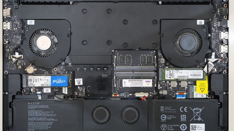 Inside of a laptop with the bottom cover removed, showing the battery pack, fans and SSD (similar laptop, not a Yoga)