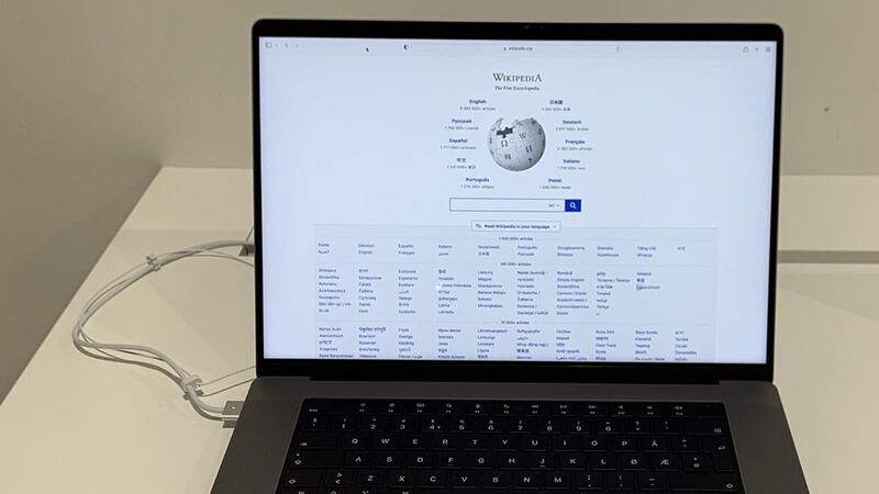 MacBook Pro 16-inch (2021) in Space Gray, open on a white store table