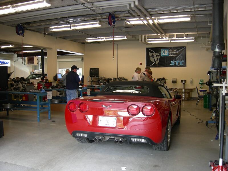 Car parked in a GM dealer technician training shop with service bays and lifts