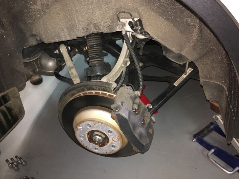 Wheel removed on a car on a lift, showing the brake rotor and caliper (similar vehicle)