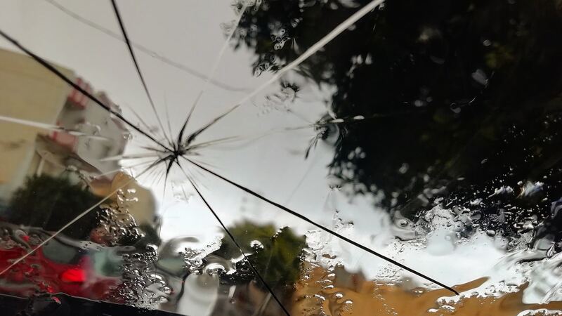 Cracked car windshield with a star break spreading across the glass