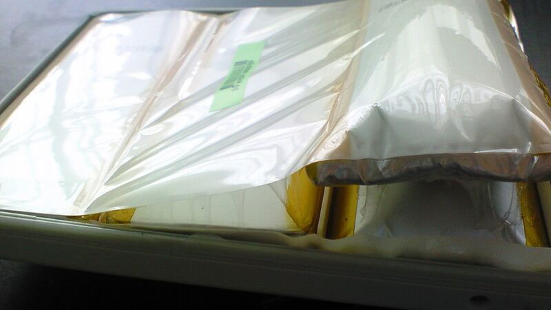 A swollen lithium-ion battery bulging inside an opened laptop (similar laptop, not a Surface)