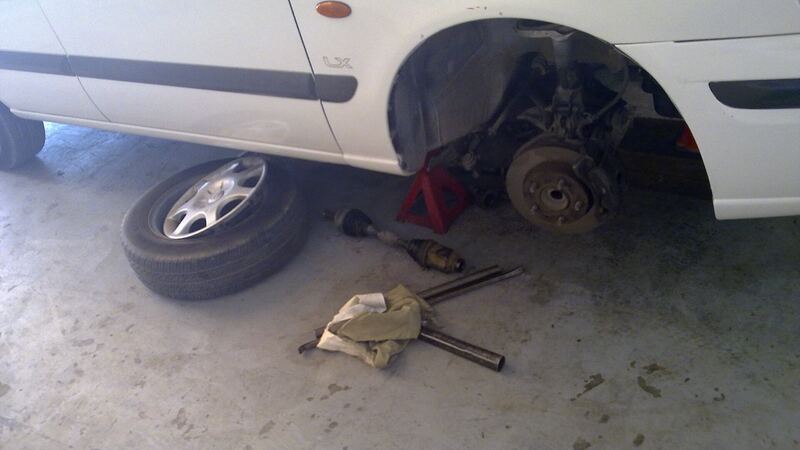Car on a jack stand with the front wheel off, showing the brake rotor and suspension