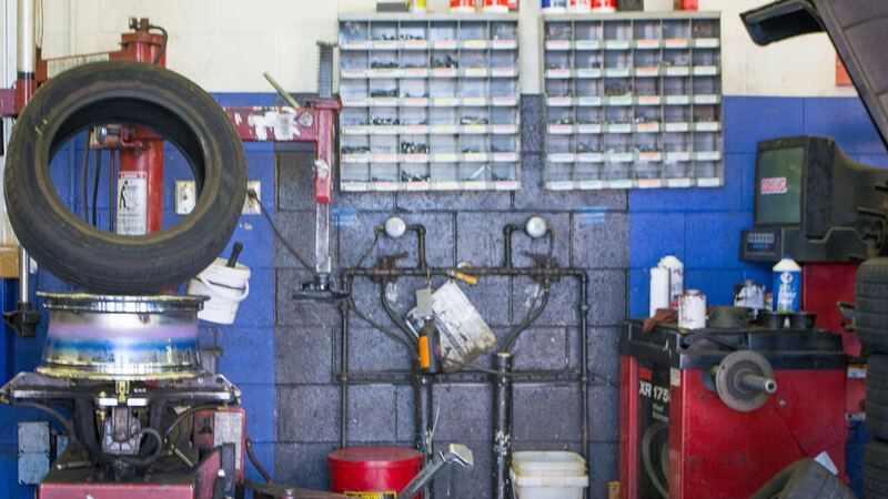 Tire being mounted on a tire changer next to a wheel balancer inside a tire shop