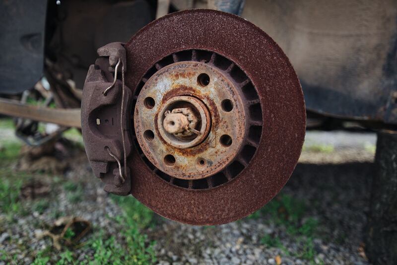 Rusty brake rotor and caliper on a vehicle with the wheel removed