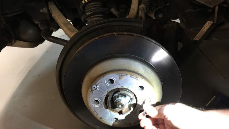 Car on a lift with the wheel off and the brake rotor being removed (similar vehicle)