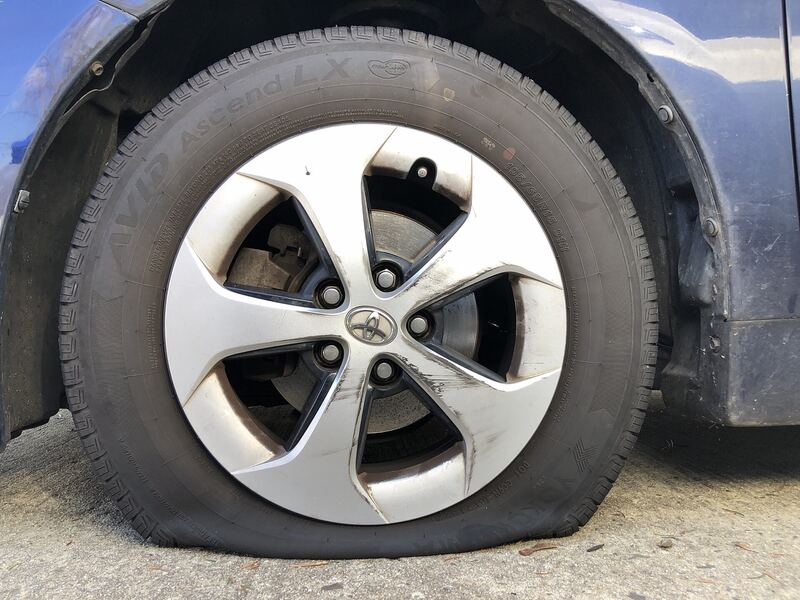 Front tire gone completely flat on a sedan parked in a driveway (similar vehicle)