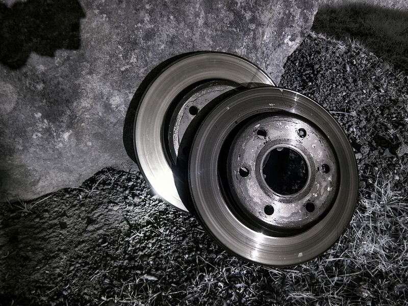 Two worn brake rotors removed from a car, set on a dark surface (similar vehicle)
