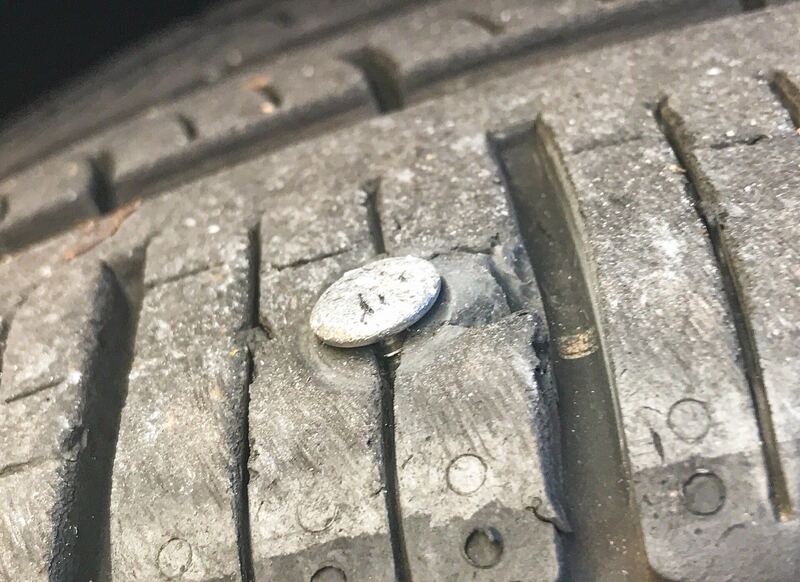 Close-up of a nail stuck in the tread of a car tire (similar vehicle)