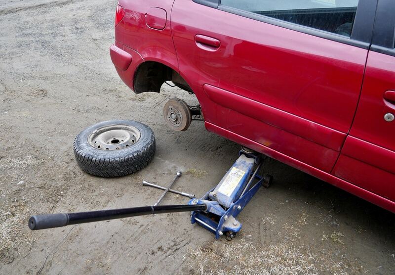 Car raised on a floor jack with one wheel removed and the tire on the ground during a tire change (similar vehicle)