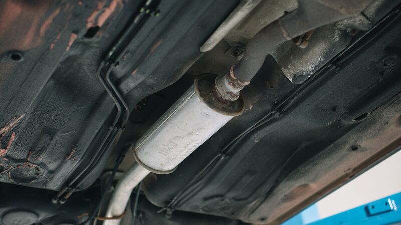 Underside of a vehicle on a garage lift showing the exhaust pipe and muffler